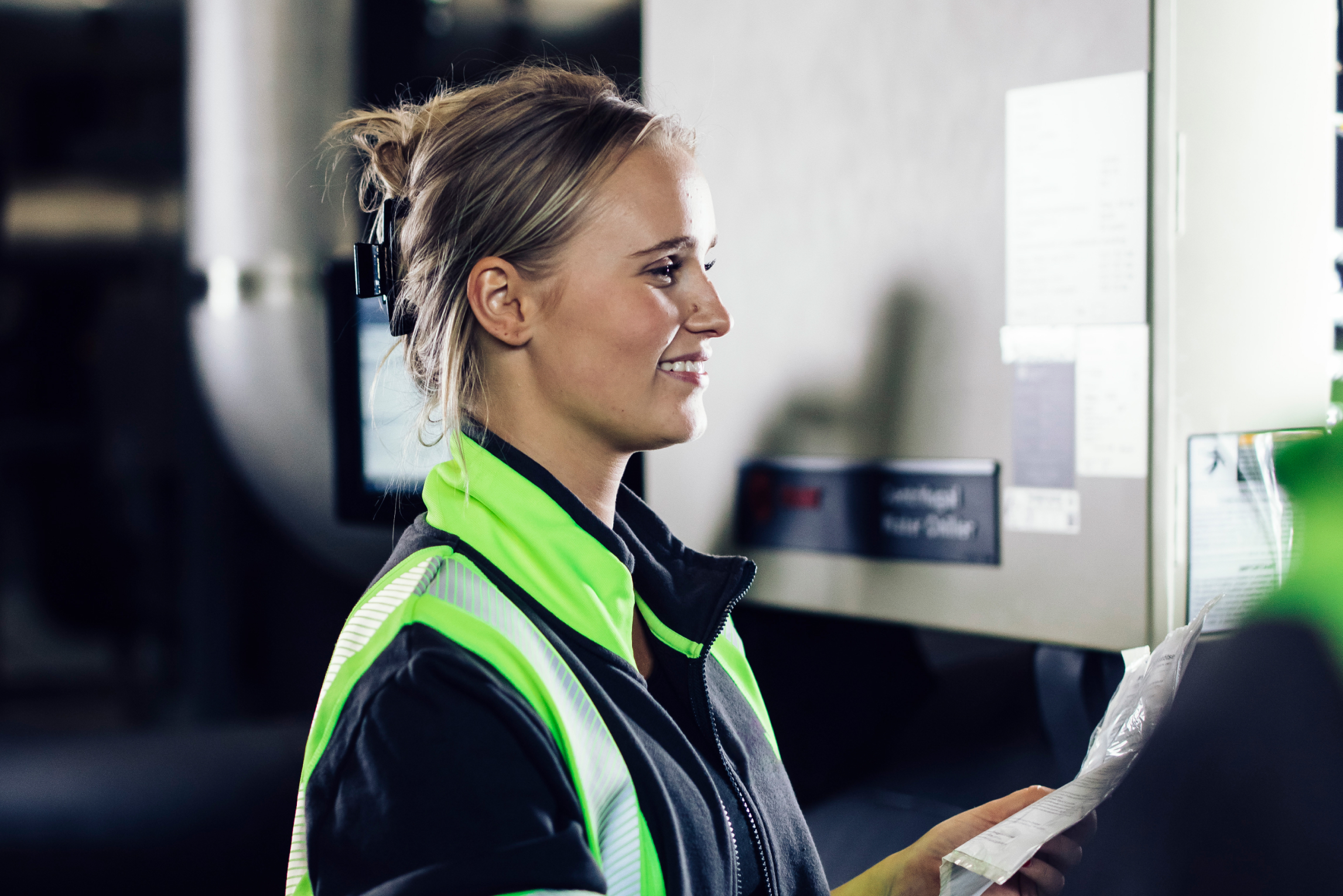 En kvinna med reflexkläder som blickar mot en panel